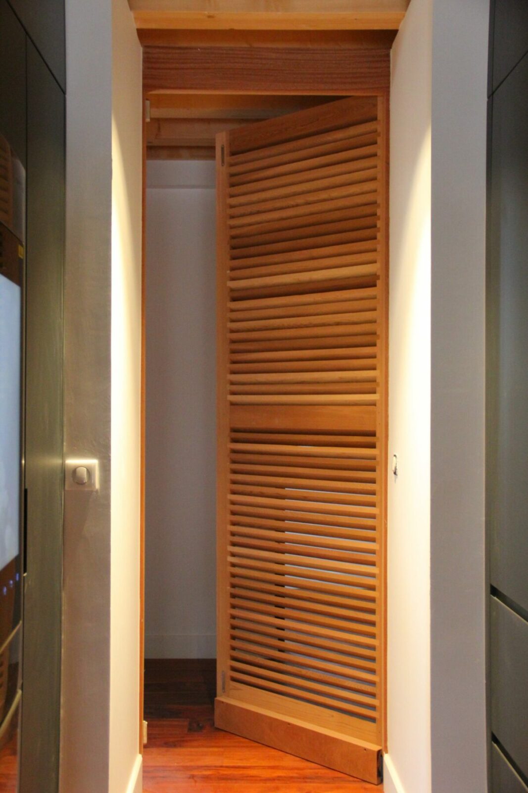 Volets Guignard en bois avec lamelles, intégrés dans un hall moderne.