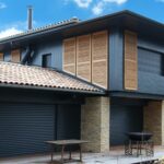 Maison moderne avec volets en bois et tuiles rouges.