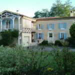 Maison avec volets bleu, Volets Guignard, et jardin fleuri.