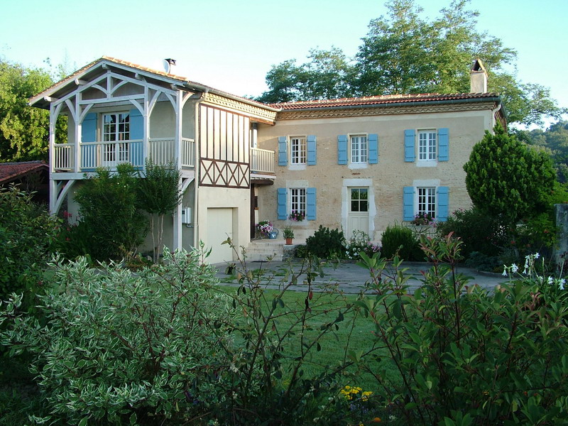 Maison avec volets bleu, Volets Guignard, et jardin fleuri.