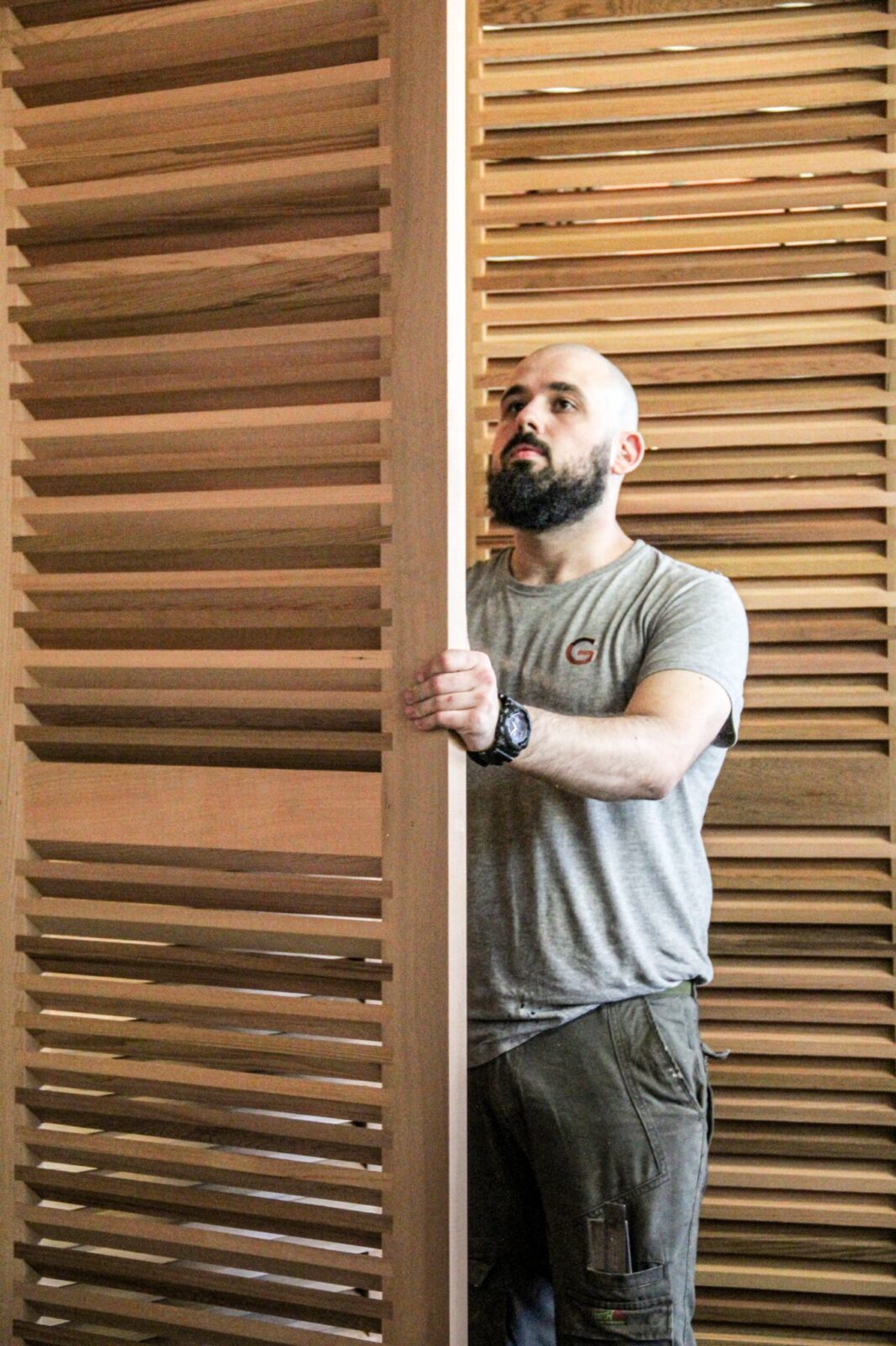 Artisan manipulant des volets Guignard en bois.