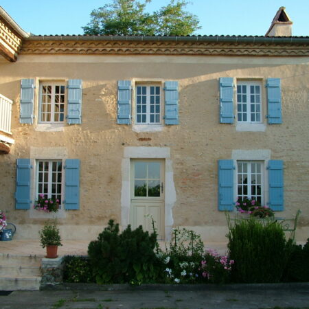 Maison traditionnelle avec volets bleus.