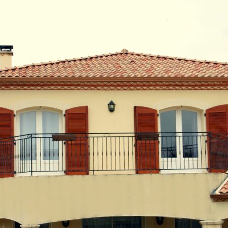 Volets rouges balcon maison tuiles