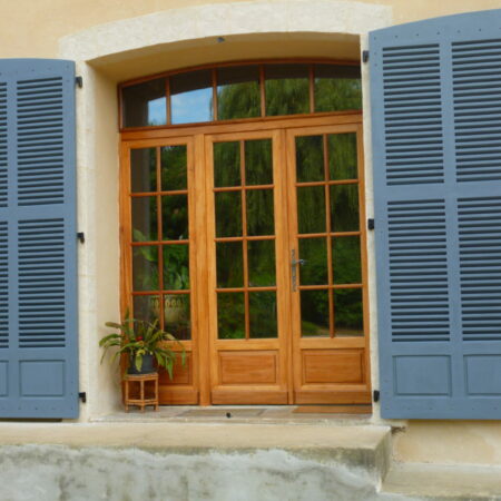 Volets bleus ouverts sur porte en bois